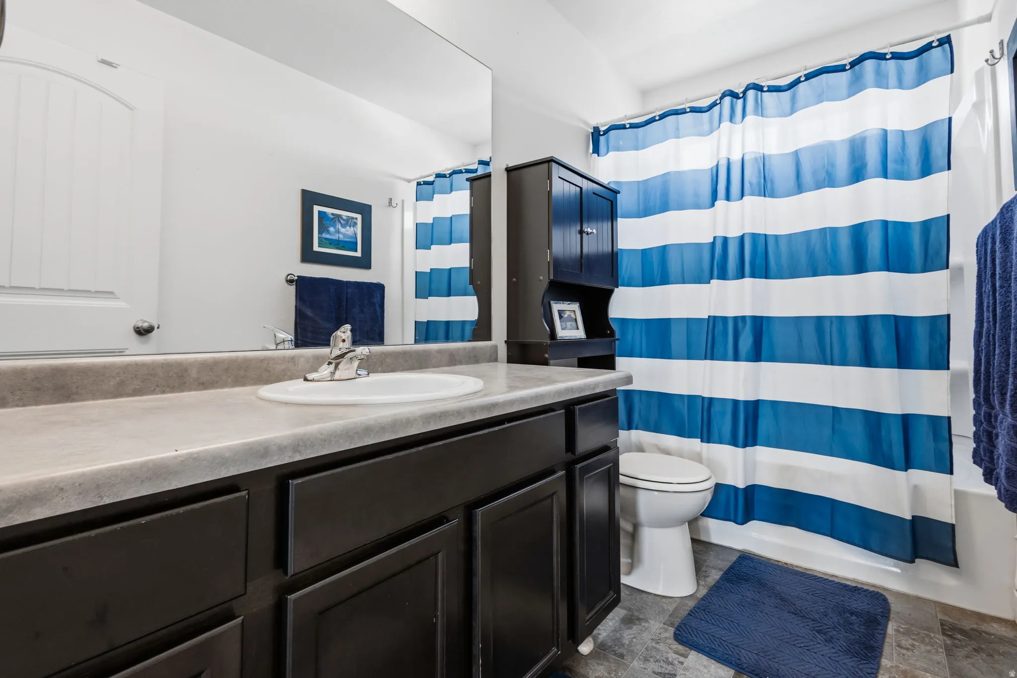 Bathroom featuring a dark wood vanity with a light-toned countertop, a built-in sink, and a large wall mirror