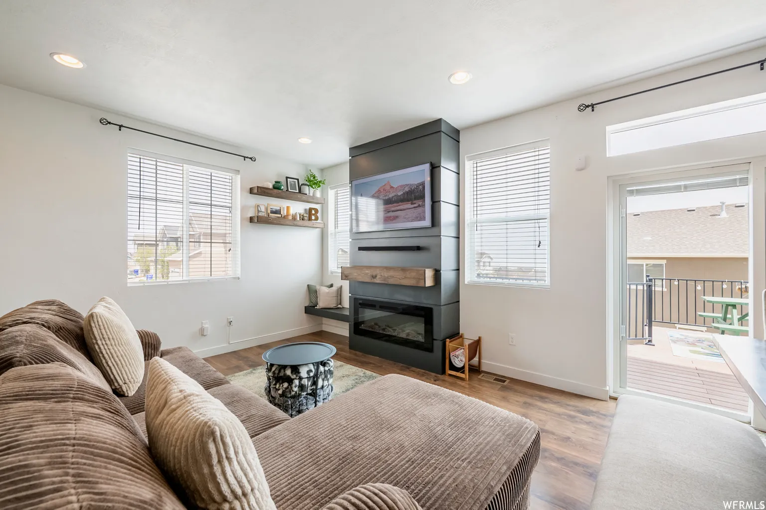 Contemporary fireplace with a wood mantel, built-in shelving, and wood-finish flooring
