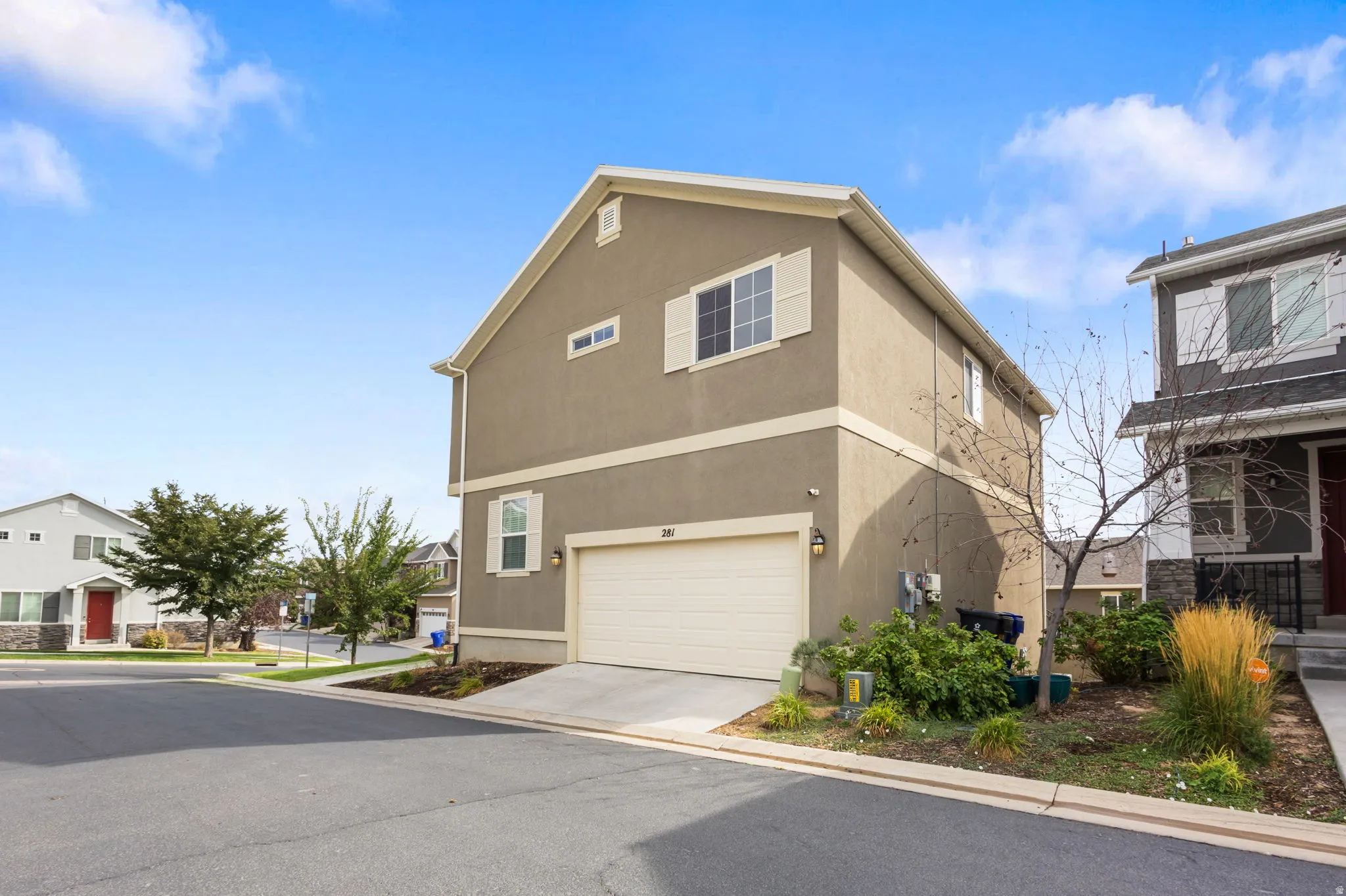 Stucco exterior with white trim, attached single-car garage, concrete driveway, and front landscaping