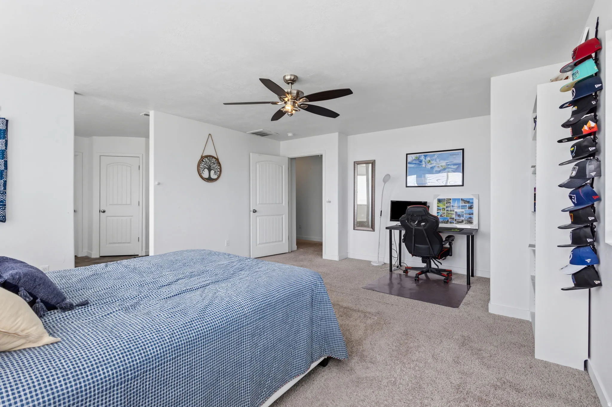 Spacious bedroom suite with neutral carpeting, ceiling fan with integrated lighting, and direct access to an ensuite bathroom