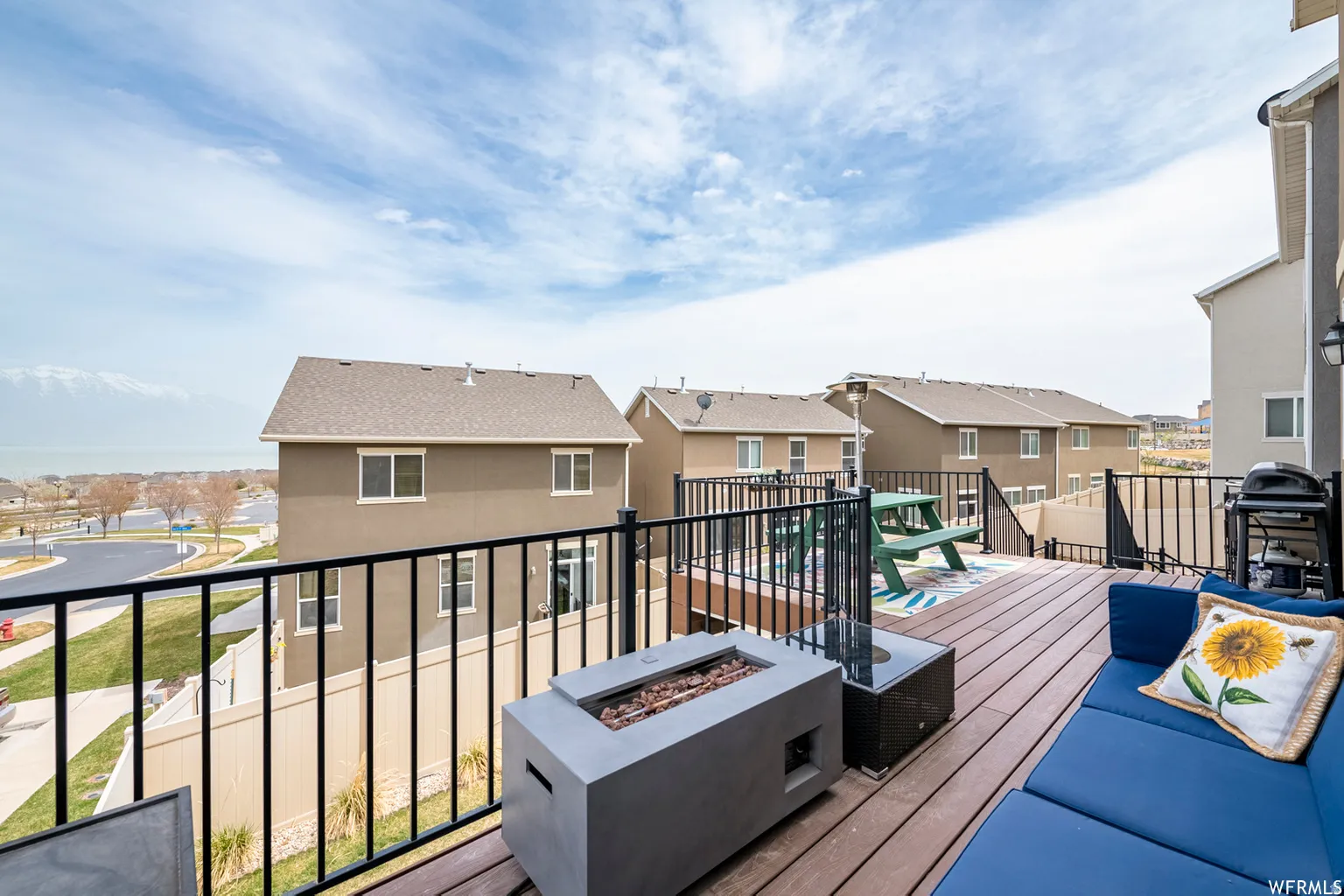 Expansive elevated deck featuring composite wood-finish flooring, black metal railings, and a built-in fire feature