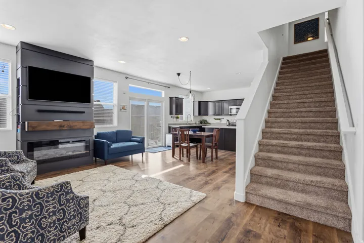 Integrated media wall with an electric fireplace, wood-finish flooring, recessed lighting, and a staircase with carpeted treads