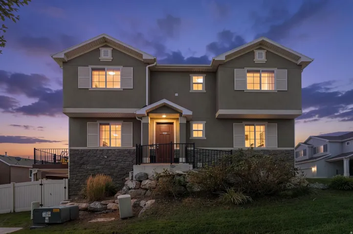 Modern two-story residence featuring a charcoal exterior with stone accents, multiple gabled rooflines, and illuminated windows