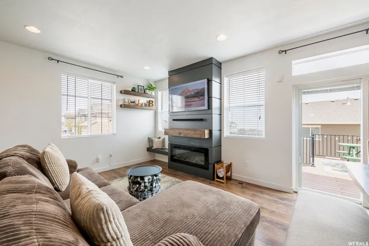 Contemporary fireplace with a wood mantel, built-in shelving, and wood-finish flooring