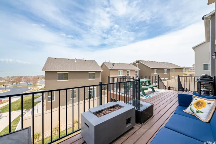 Expansive elevated deck featuring composite wood-finish flooring, black metal railings, and a built-in fire feature