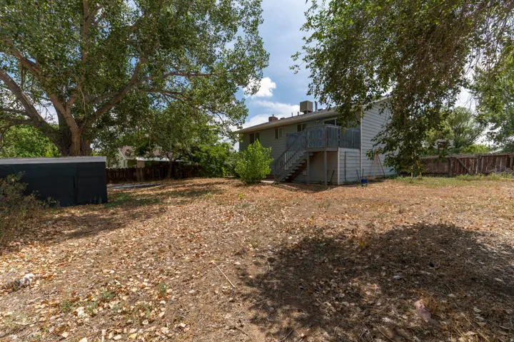 Expansive backyard featuring mature trees, a multi-level deck with stairs, a shed, and privacy fencing