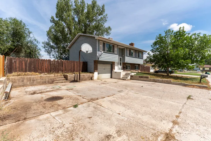 Spacious driveway with ample parking and turnaround space, complemented by mature landscaping and established trees throughout the property