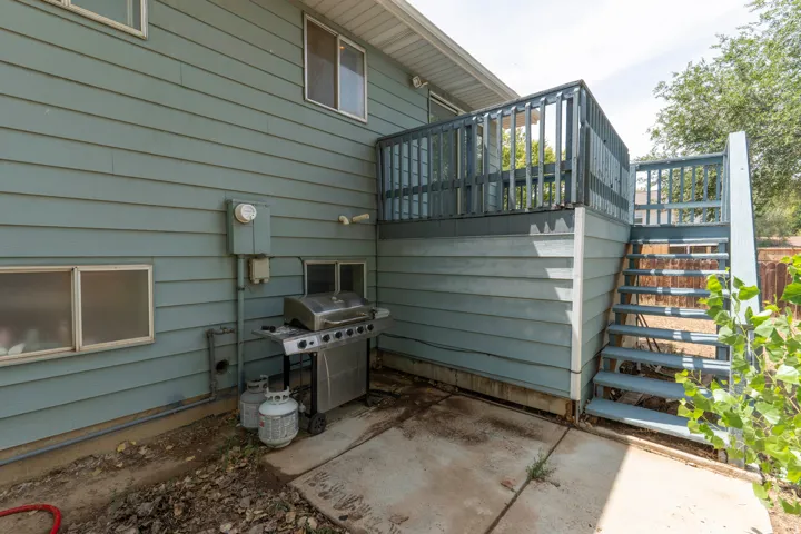 Outdoor living space featuring a composite deck with black railings, built-in gas grill, concrete patio, and mature landscaping