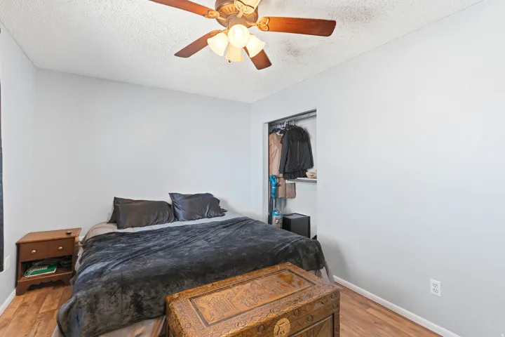 Wood-finish flooring, ceiling fan, and open closet with shelving and hanging rod