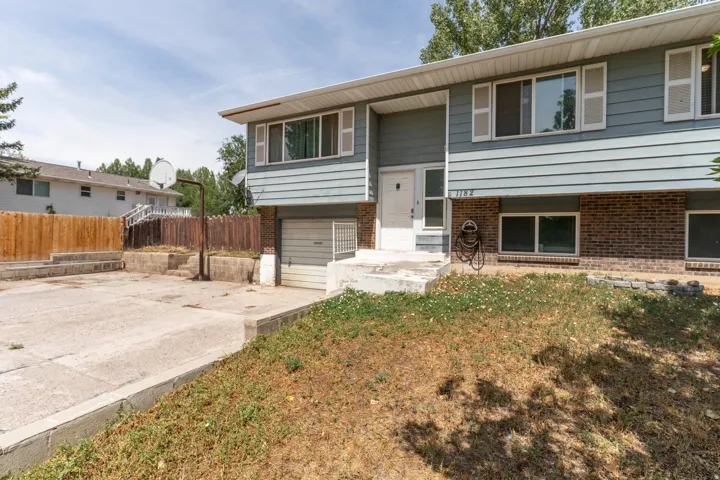 Split-level home featuring a newly poured concrete driveway, attached two-car garage, and brick lower-level exterior