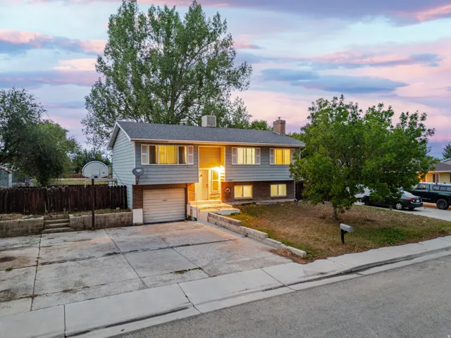 Split-level residence featuring a brick and siding exterior, an attached garage, a paved driveway, and mature landscaping