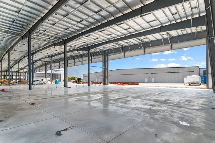 Expansive warehouse interior with a concrete floor, exposed metal structural beams, and a high-span metal ceiling