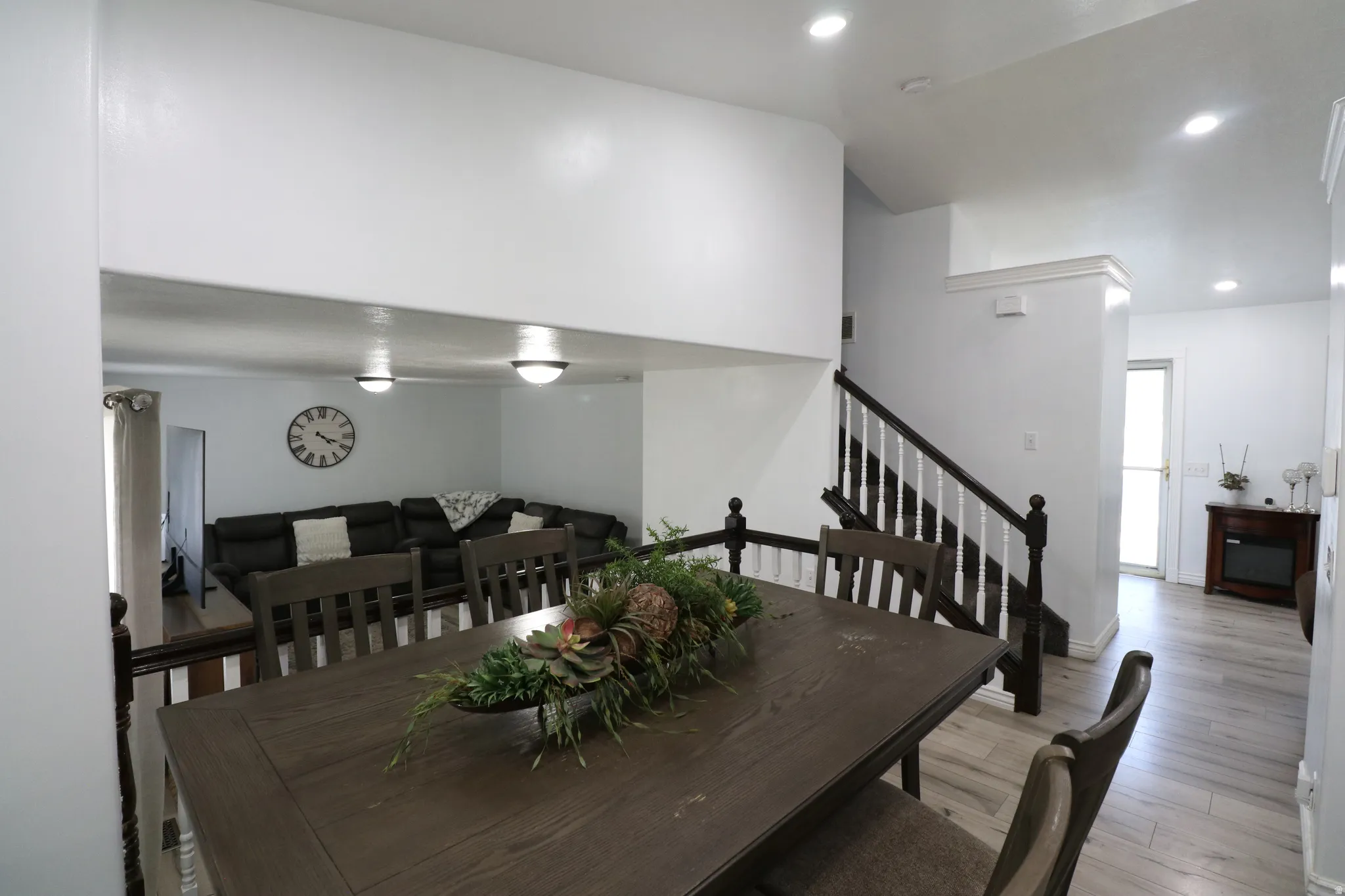 Wood-finish flooring throughout, recessed lighting, and a staircase with dark wood newel posts and handrail