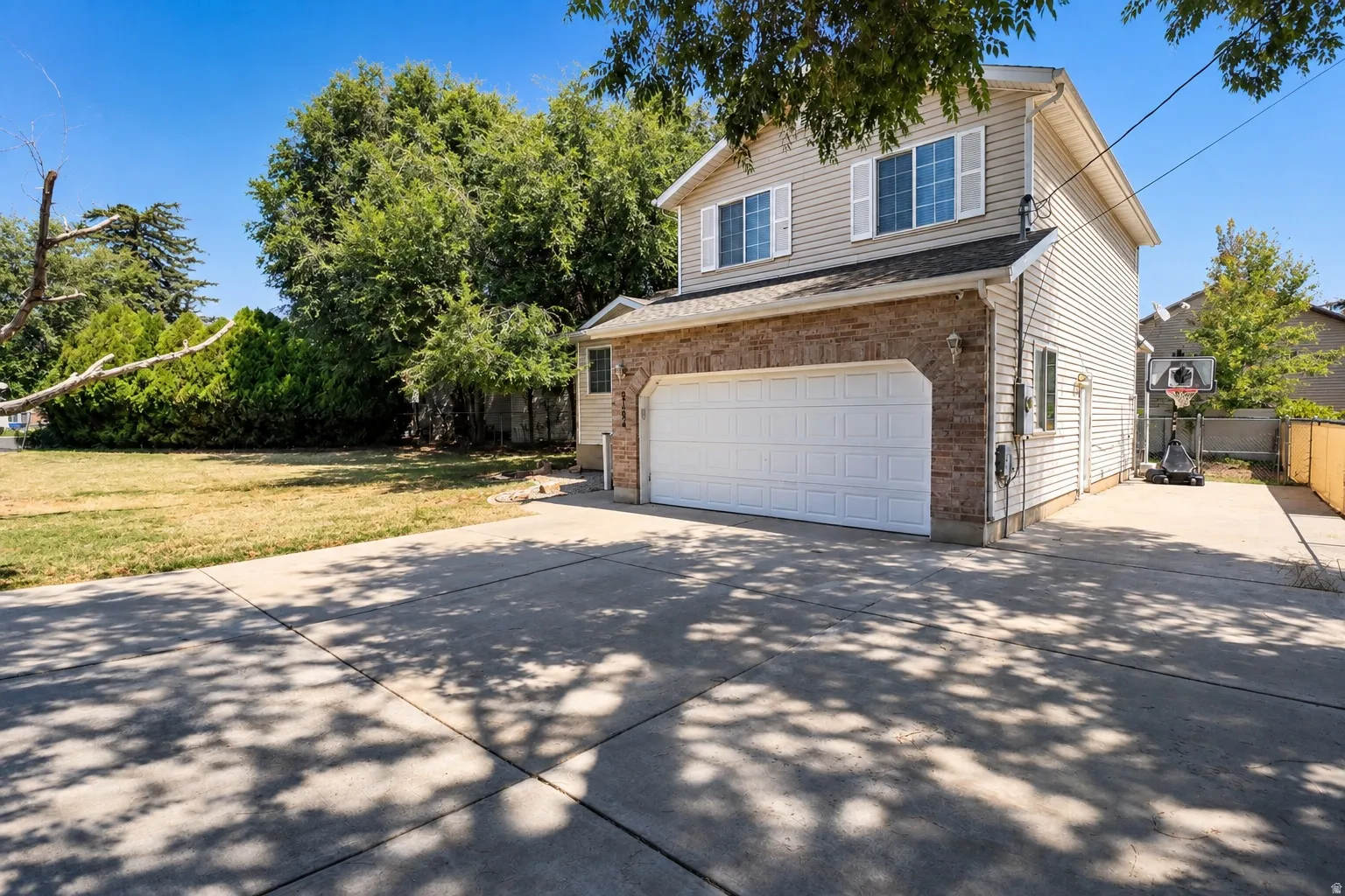 Two-story residence featuring a two-car garage with a white door, stone veneer, and horizontal siding