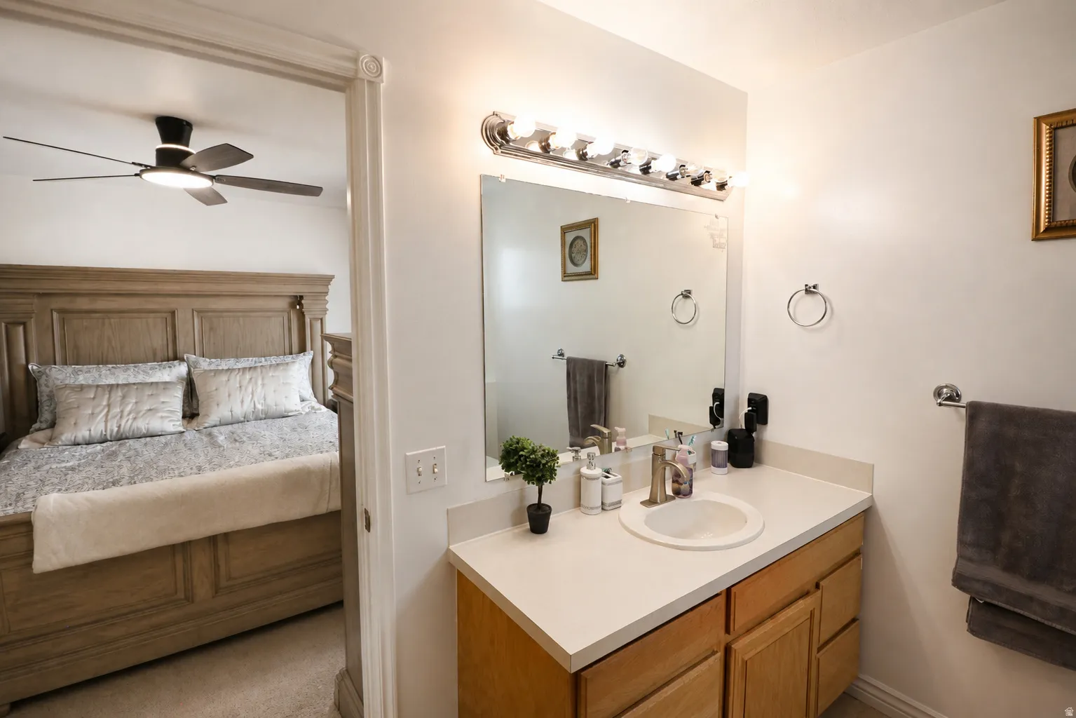 Bathroom vanity with a single sink, light-toned countertop, and wood-finish cabinetry