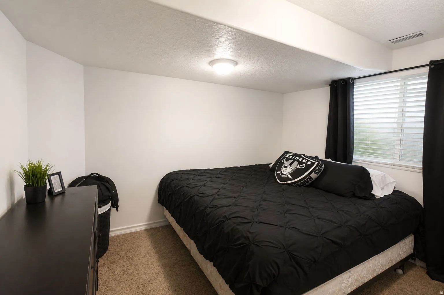 Carpeted room with a single window, overhead lighting, and white walls