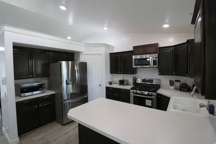 Kitchen featuring dark wood cabinetry, light countertops, stainless steel appliances, and recessed lighting