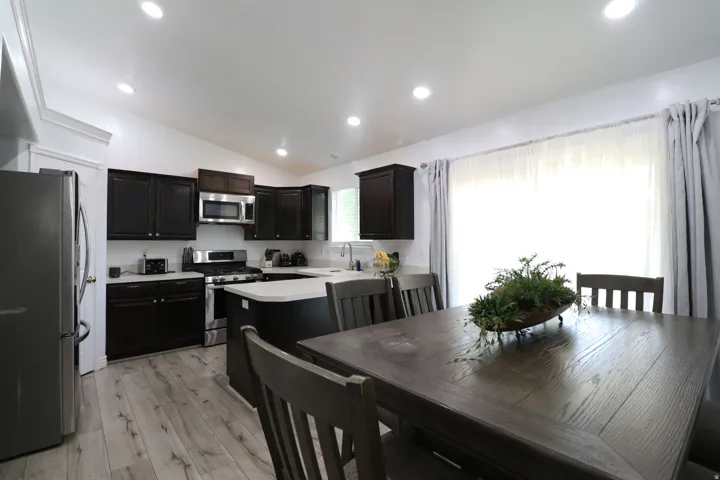 Kitchen featuring dark wood cabinetry, stainless steel appliances, light-toned countertops, and wood-finish flooring