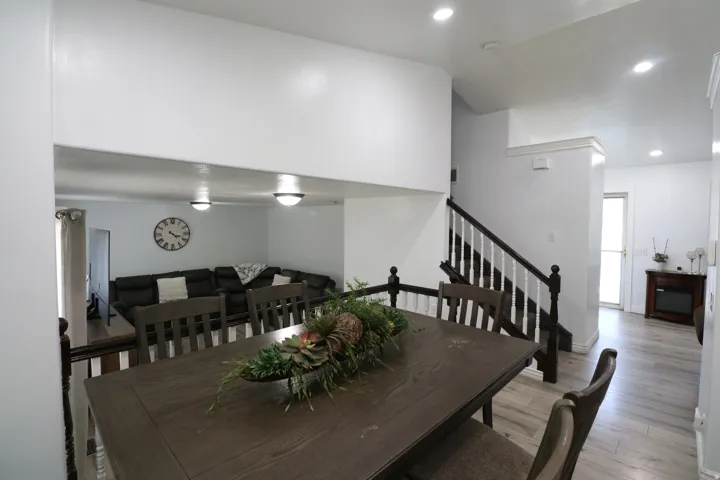 Wood-finish flooring throughout, recessed lighting, and a staircase with dark wood newel posts and handrail