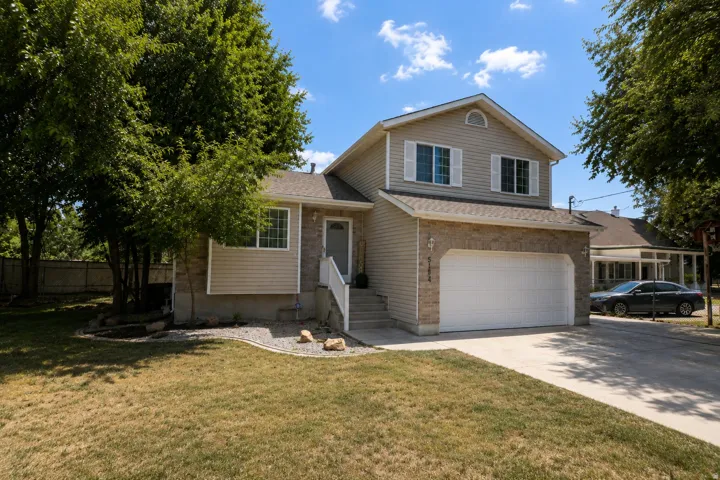 Two-story exterior featuring a stone and siding facade, attached two-car garage, and concrete driveway