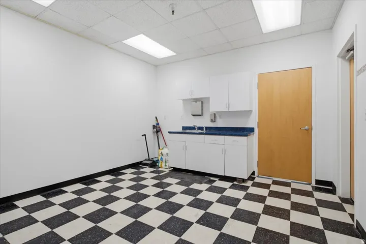 White cabinetry with a countertop sink, checkerboard flooring, and recessed lighting