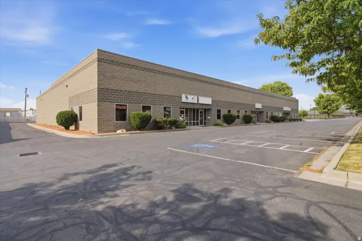 Large commercial building featuring a block exterior, multiple entry points, a substantial paved parking area, and mature landscaping