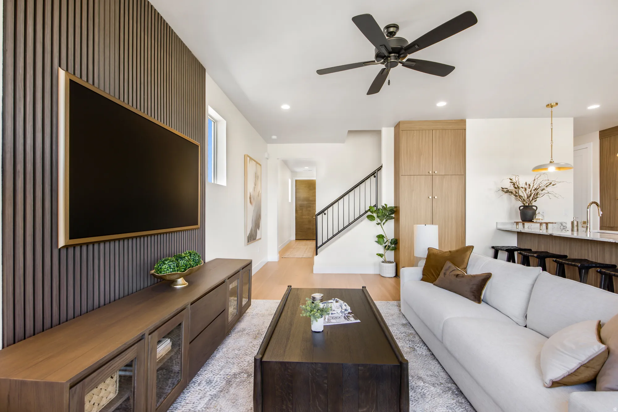 Open-concept living space with wood-finish flooring, a contemporary ceiling fan, and recessed lighting