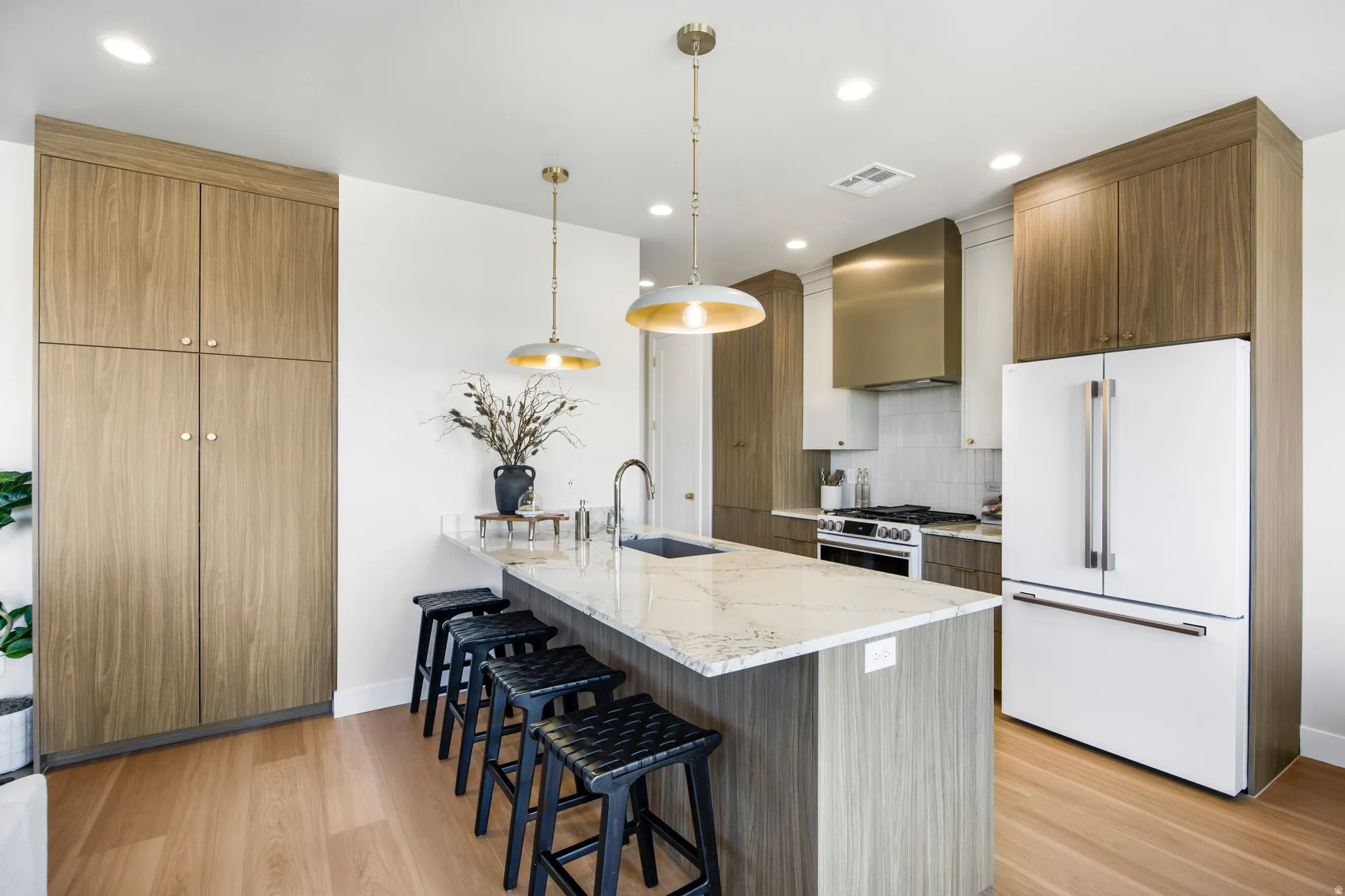 Kitchen featuring an oversized island with a stone countertop, a stainless steel range with a professional-grade hood, wood-finish cabinetry, and recessed lighting