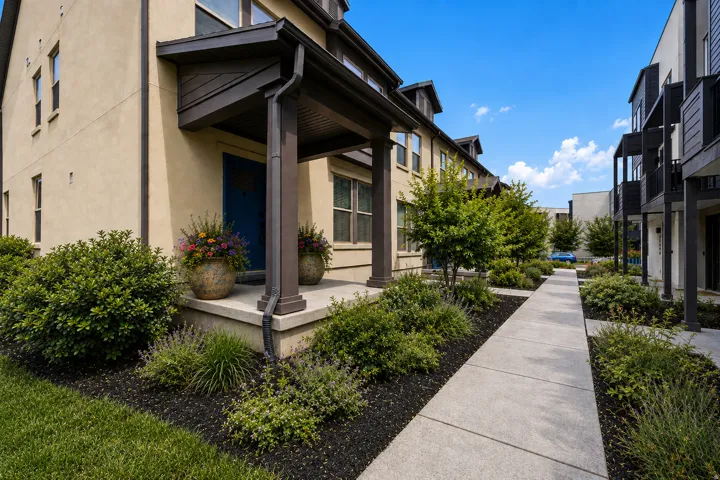 Stucco exterior with a covered porch, concrete walkway, and landscaped garden beds