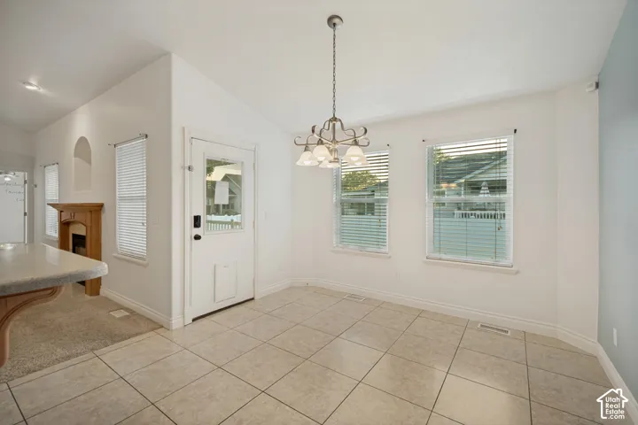 Tiled flooring with a classic lighting fixture, two windows with blinds, a white door with a window, and a built-in fireplace with a wood-finish mantel