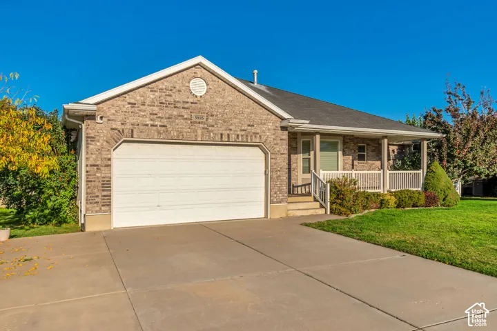 Brick exterior with an attached garage, covered front porch, and concrete driveway