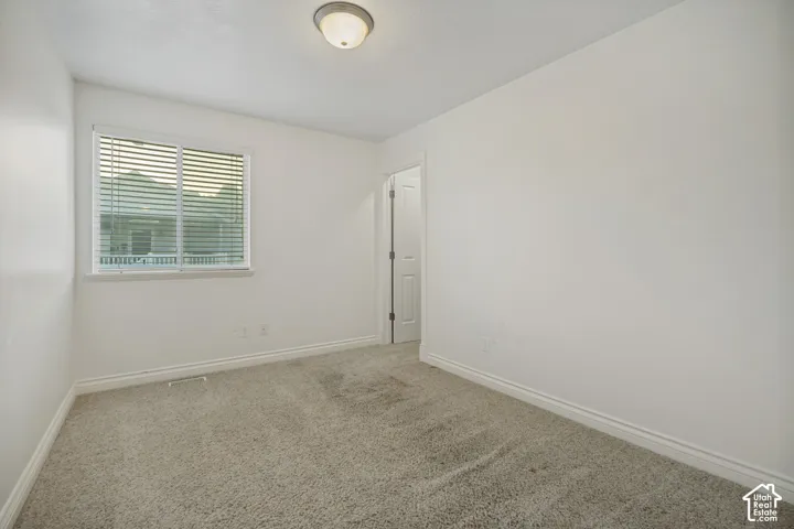 Neutral wall paint, textured carpet flooring, single window with blinds, overhead flush mount light fixture