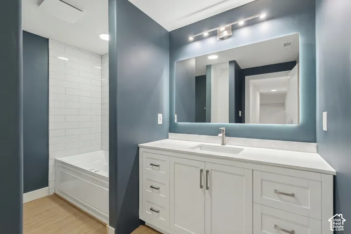 White shaker-style vanity with a single basin, light-colored countertop, and brushed nickel faucet