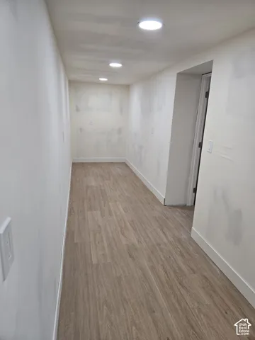 Recessed ceiling lighting, wood-finish flooring, white wall finishes, and white baseboards