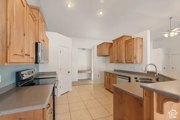 Kitchen featuring wood cabinetry, stainless steel appliances, tiled flooring, and a double basin sink with a gooseneck faucet