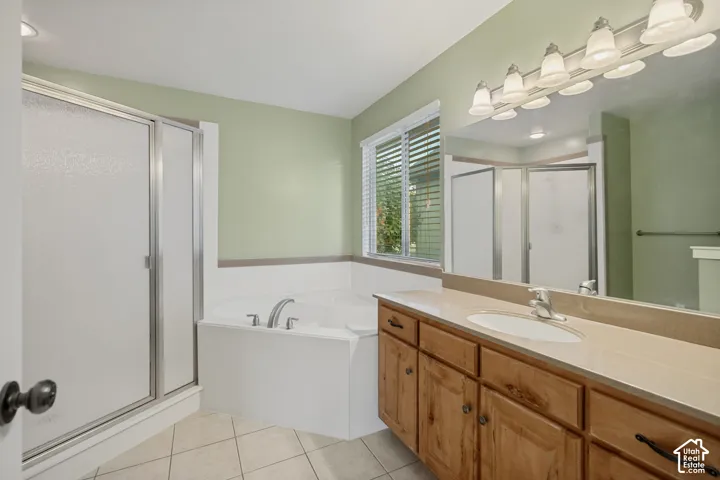 Built-in soaking tub, separate shower with frosted glass enclosure, double vanity with wood cabinetry, and a large wall-mounted mirror