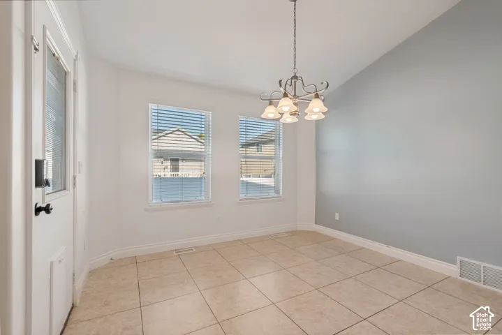 Tiled flooring, two windows with blinds, a decorative chandelier, and a two-tone wall finish