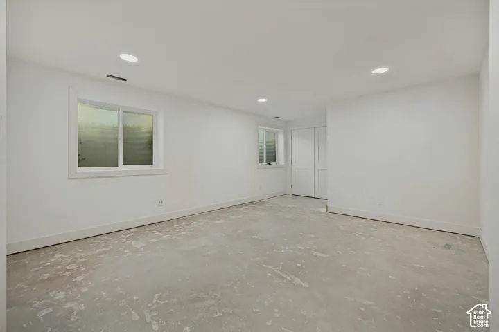 Spacious room with white walls, recessed ceiling lighting, and two windows