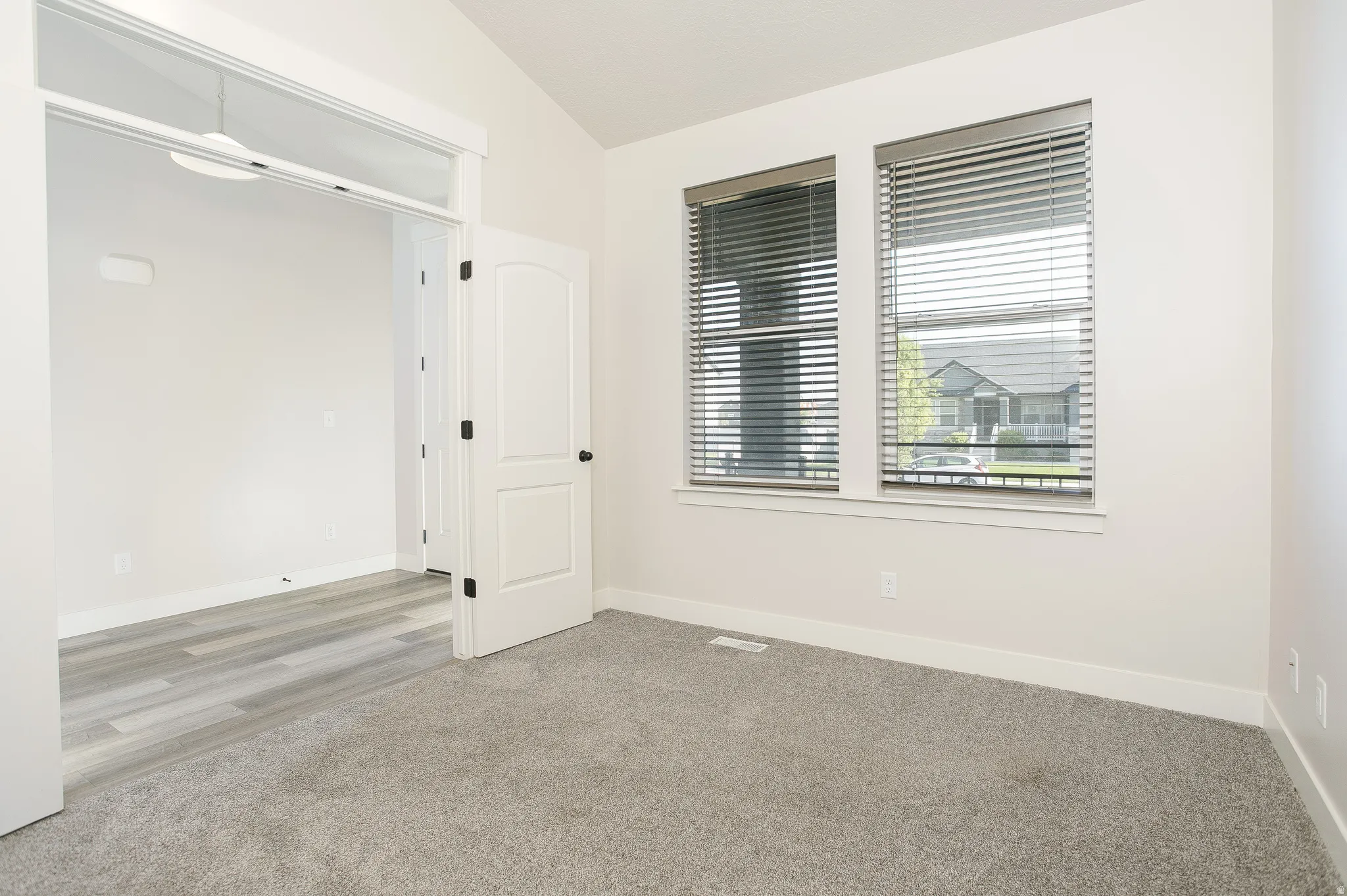 Plush grey carpeting, dual windows with blinds, and white trim throughout
