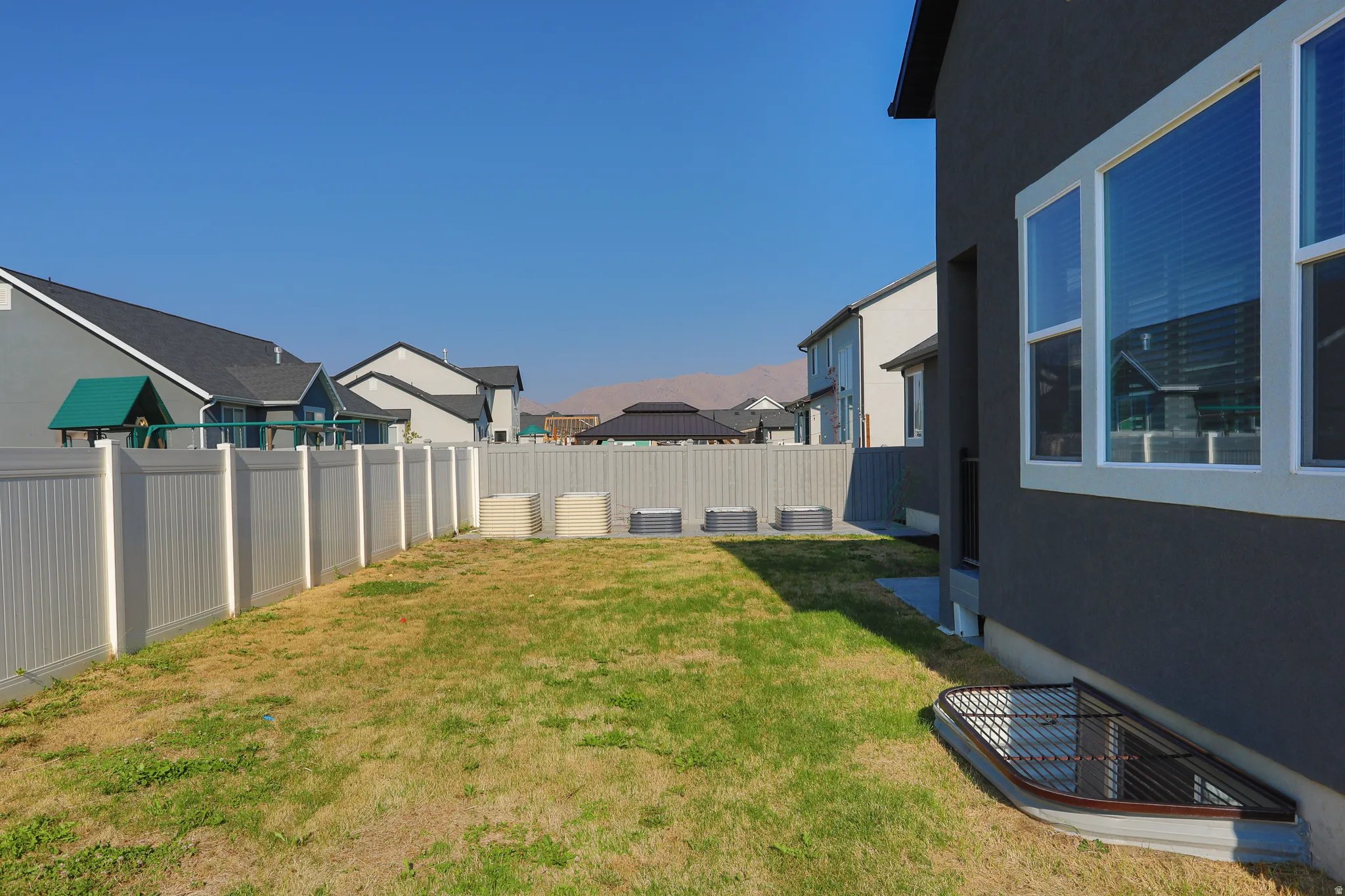 Private backyard with a vinyl privacy fence, stucco exterior, and multi-pane windows