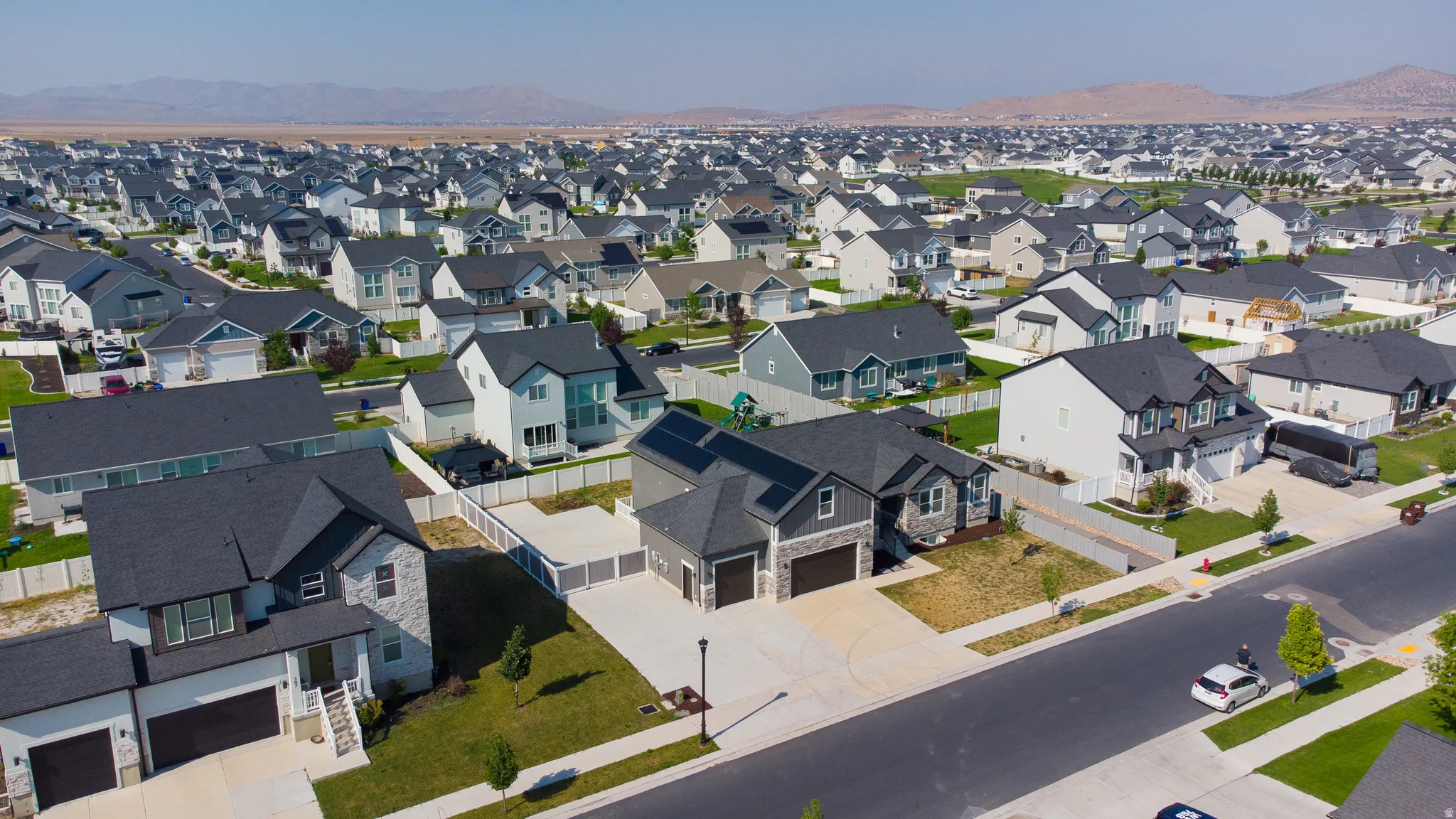 Expansive residential area featuring contemporary homes with dark shingle roofs, paved streets, and sidewalks