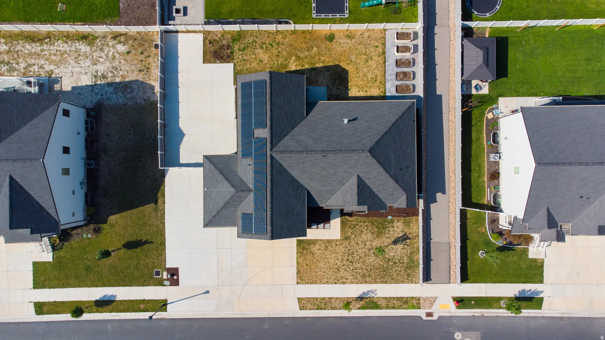 Residential property featuring a shingled roof, solar panels, concrete driveway, and front lawn