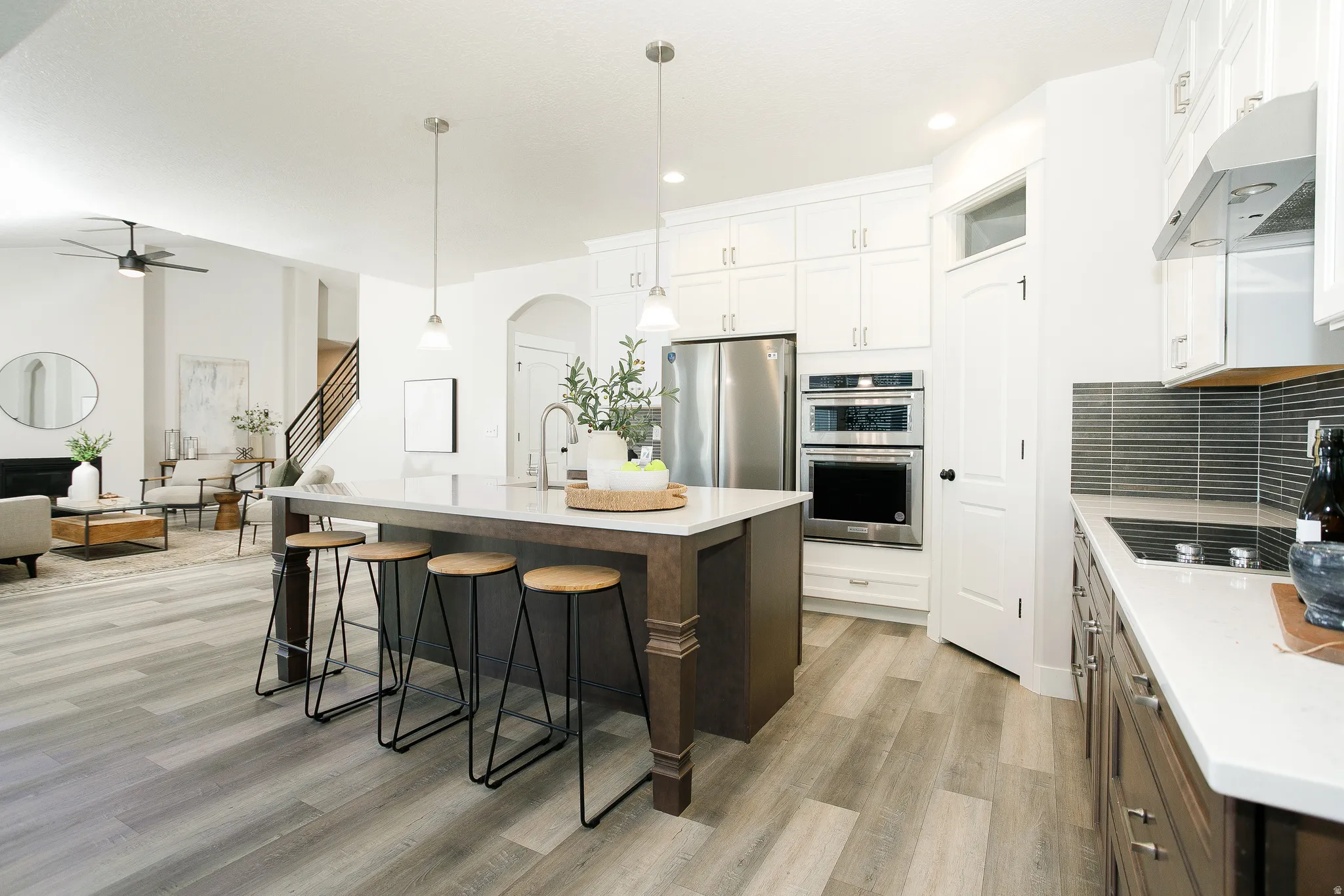 Open-concept living space featuring wood-finish flooring and a central kitchen island with pendant lighting