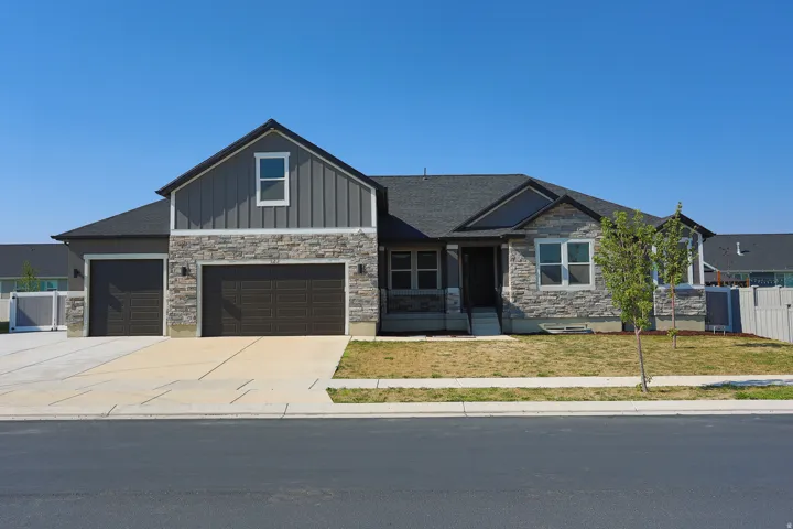 Contemporary exterior featuring a stone and vertical siding facade, dark asphalt shingle roof, attached two-car garage, and a concrete driveway