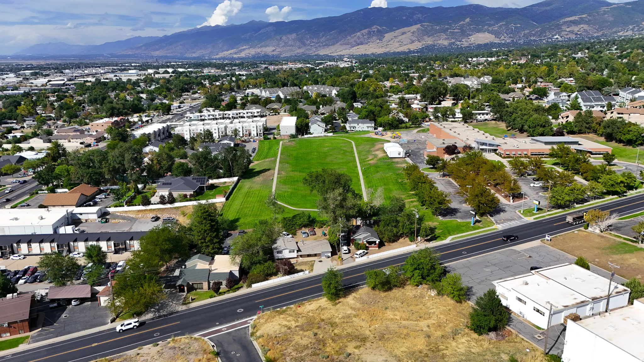 Mountain backdrop, established neighborhood, residential structures, commercial buildings, paved roadways
