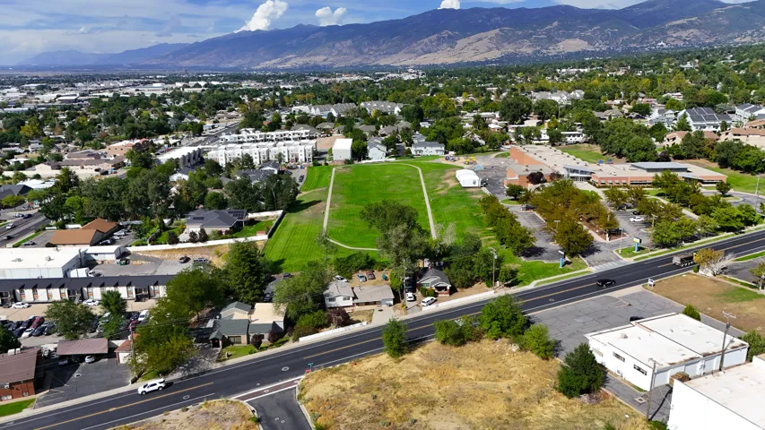 Mountain backdrop, established neighborhood, residential structures, commercial buildings, paved roadways