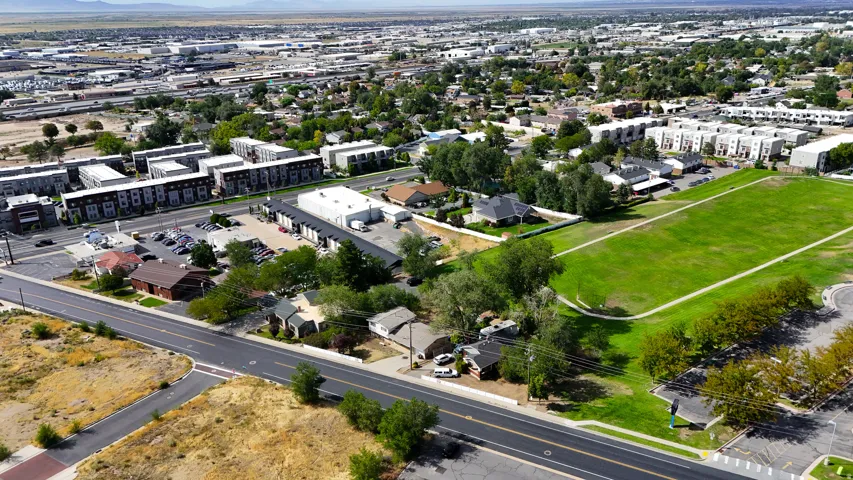 Aerial perspective showcasing a mixed-use neighborhood with residential buildings, commercial structures, and a large green space