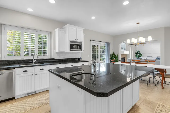 Kitchen featuring a central island, dark granite countertops, white cabinetry, integrated microwave, and stainless steel appliances