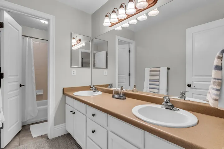 Upstairs Dual basin vanity with white cabinetry and a full-width mirror