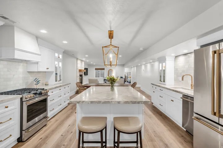 Basement Chef's kitchen featuring a professional-grade gas range, stainless steel appliances, white cabinetry with hardware accents, and a sprawling island